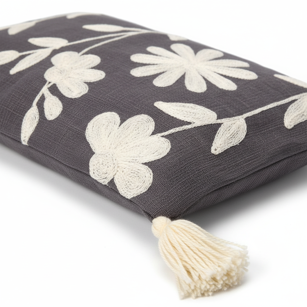 Close-up of white daisy appliqué embroidery on charcoal linen with tassel